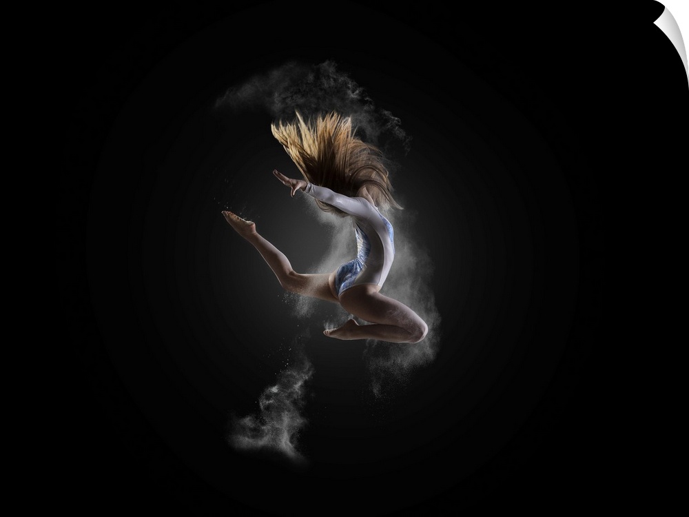 A gymnast leaps into the air, with white powder around her.