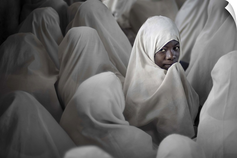 A young girl in Tanzania turns around, among other women wearing veils.