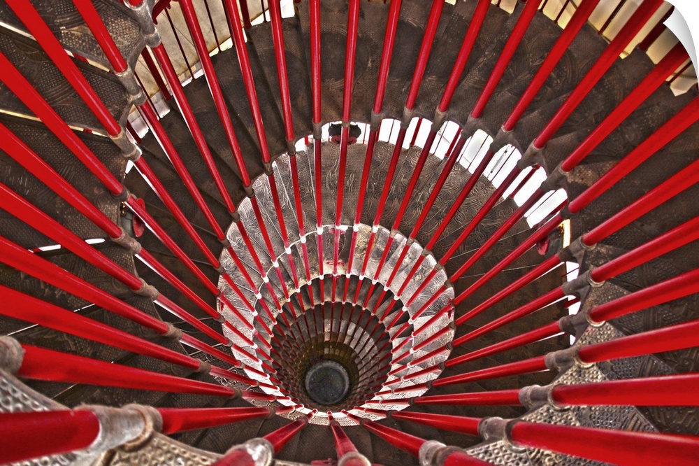 A massive spiral staircase lined with bright red banister rails.