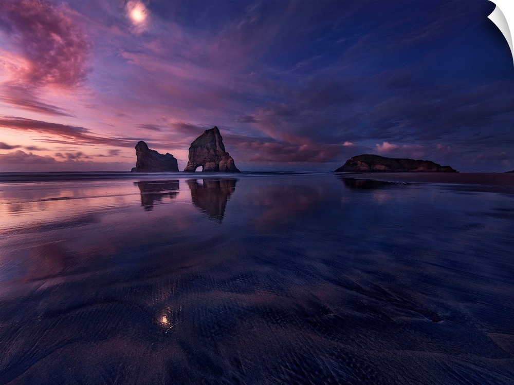 Low tide with large sea stacks and a colorful sky at dusk, Golden Bay, New Zealand.