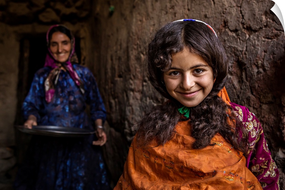 A smiling young girl with her mother standing behind her, Iran.