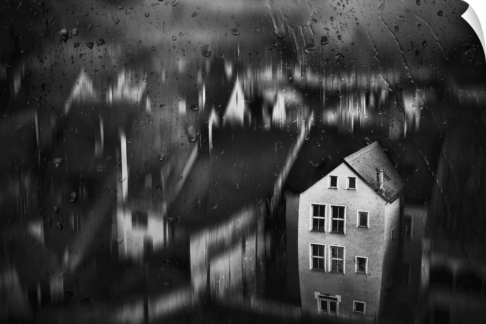 View through a window with raindrops of a blurred village scene, with one house in focus.
