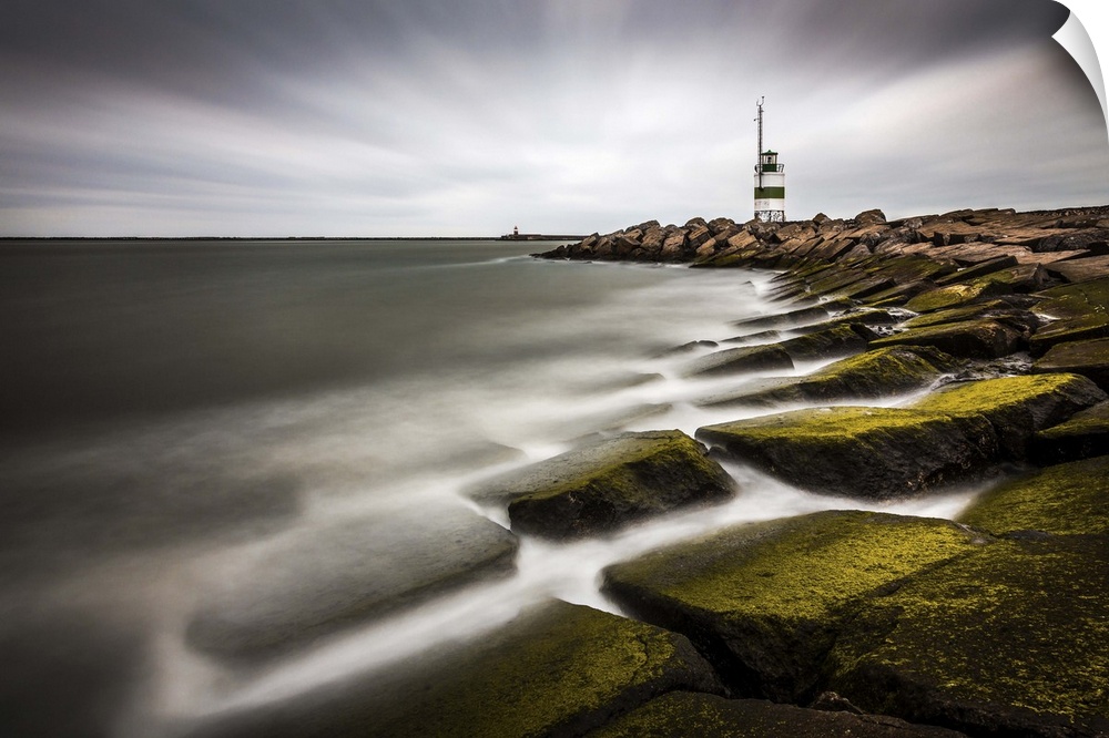 Lighthouse on the rocky moss covered shoreline of IJmuiden, Netherlands.