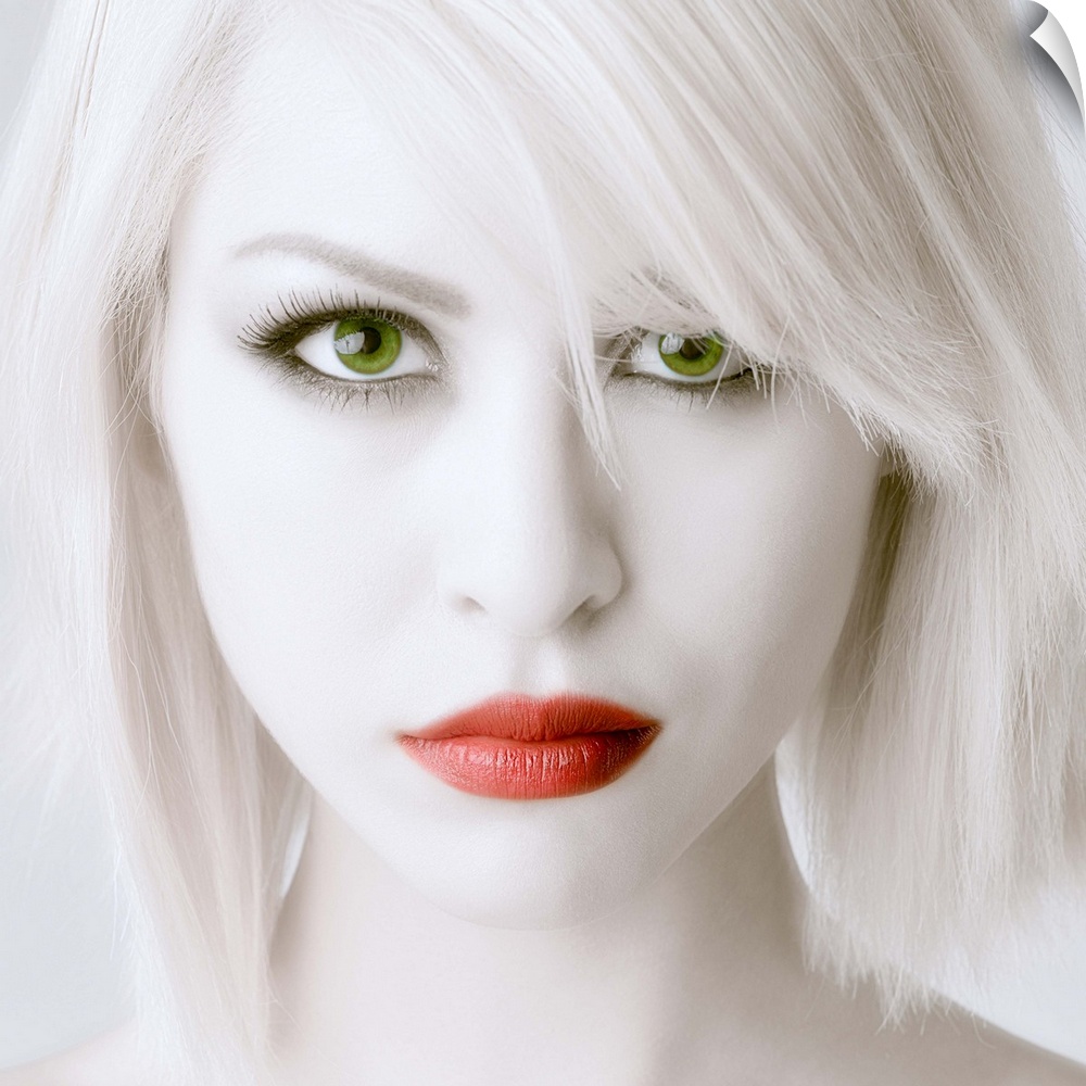 Portrait of a woman with stark white skin and hair, large green eyes, and red lips.