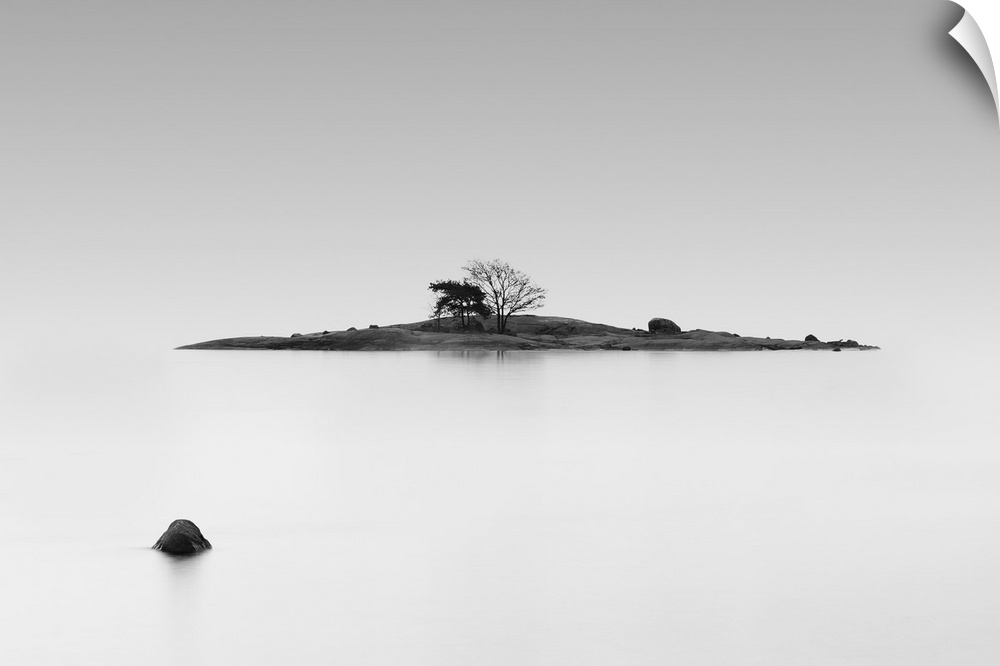 Black and white photo of a small island in the middle of still water, Finland.
