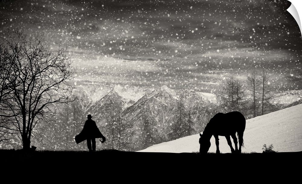 A silhouette of a grazing horse with a figure walking toward it in the falling snow.