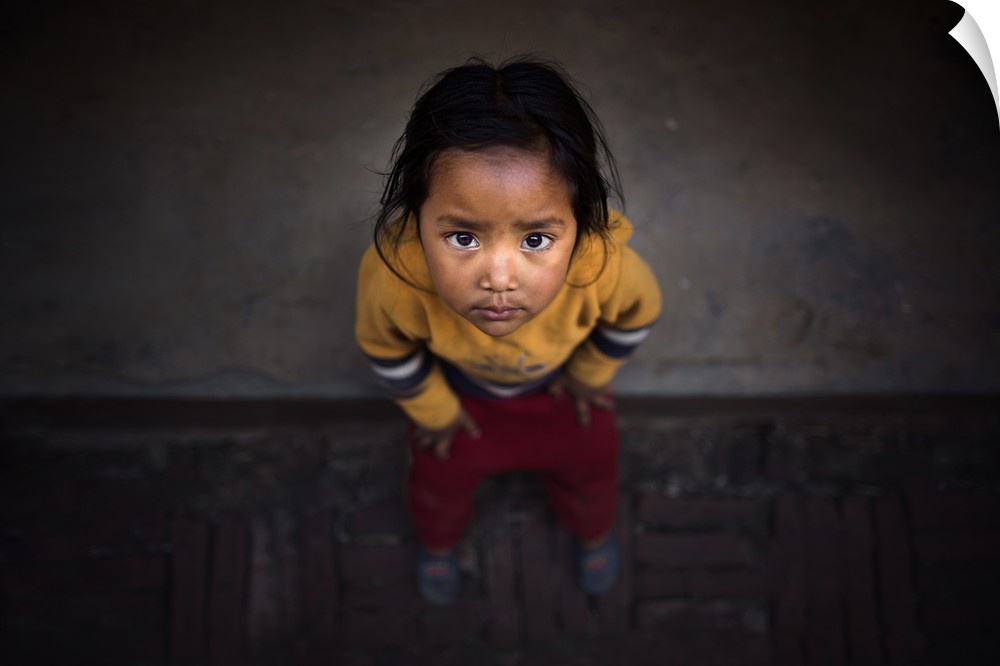 A young Nepalese girl looking up with large dark eyes.