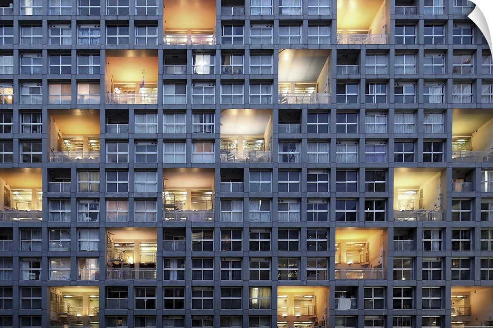 The side of a building filled with windows, and a repeating pattern of lit balconies.