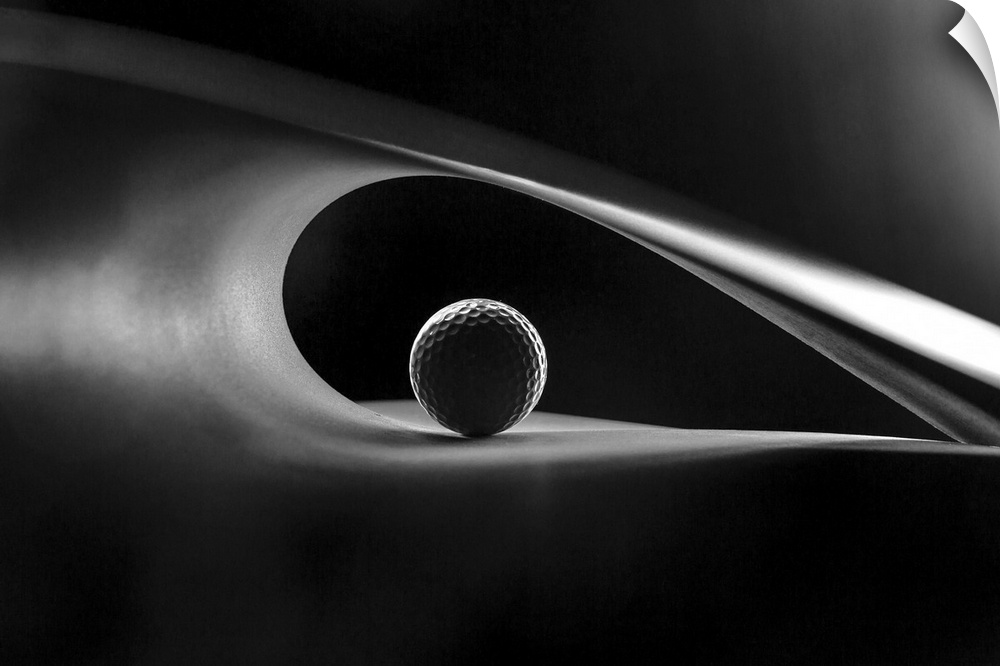A still-life of a golf ball in the curve of an abstract shape.