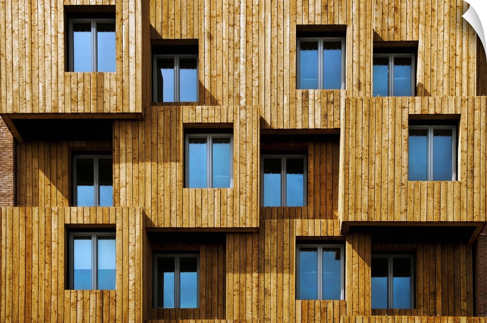 Architectural photograph of a unique wooden facade  with windows reflecting the blue sky, Wales.