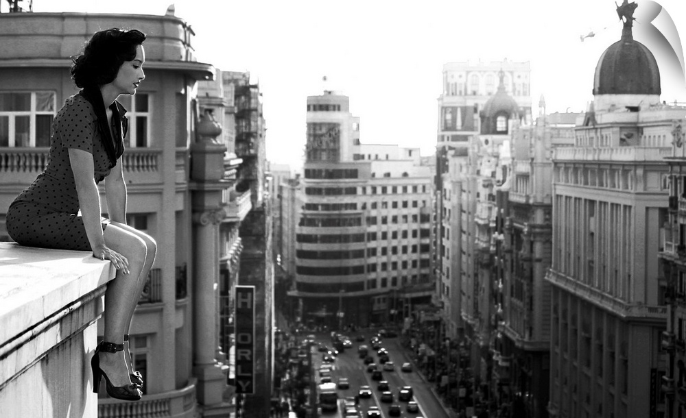A woman sits on a ledge overlooking  the streets of Madrid.