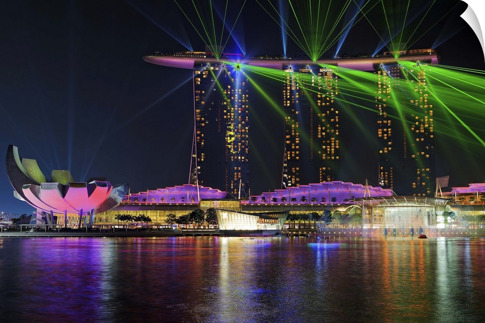 The neon lights of the city enhance the vivid laser show on Marina Bay in Singapore.