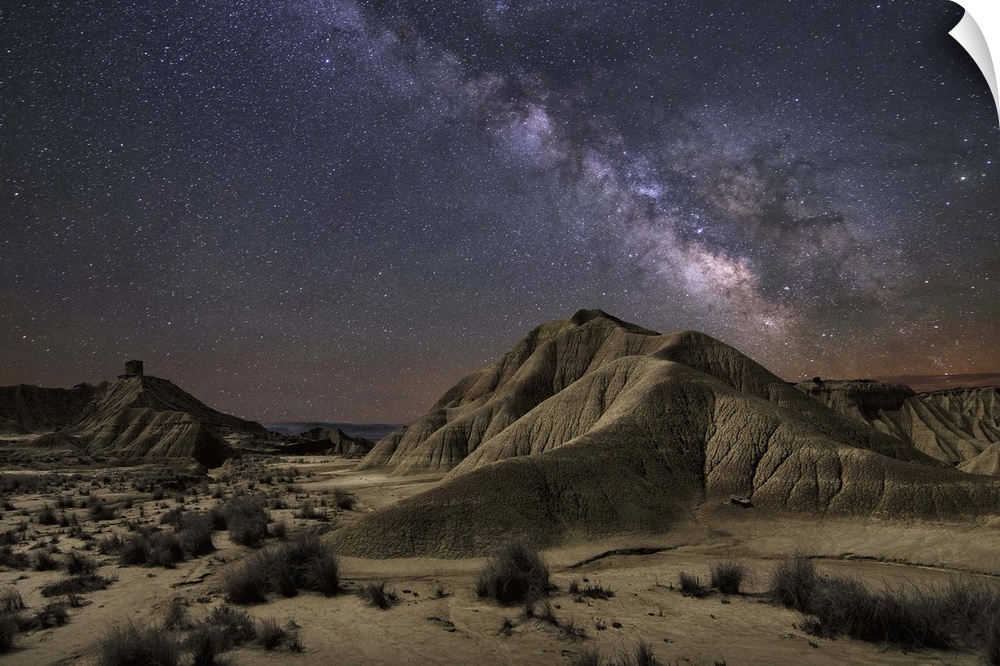 The Milky Way galaxy illuminated over a rocky desert landscape.