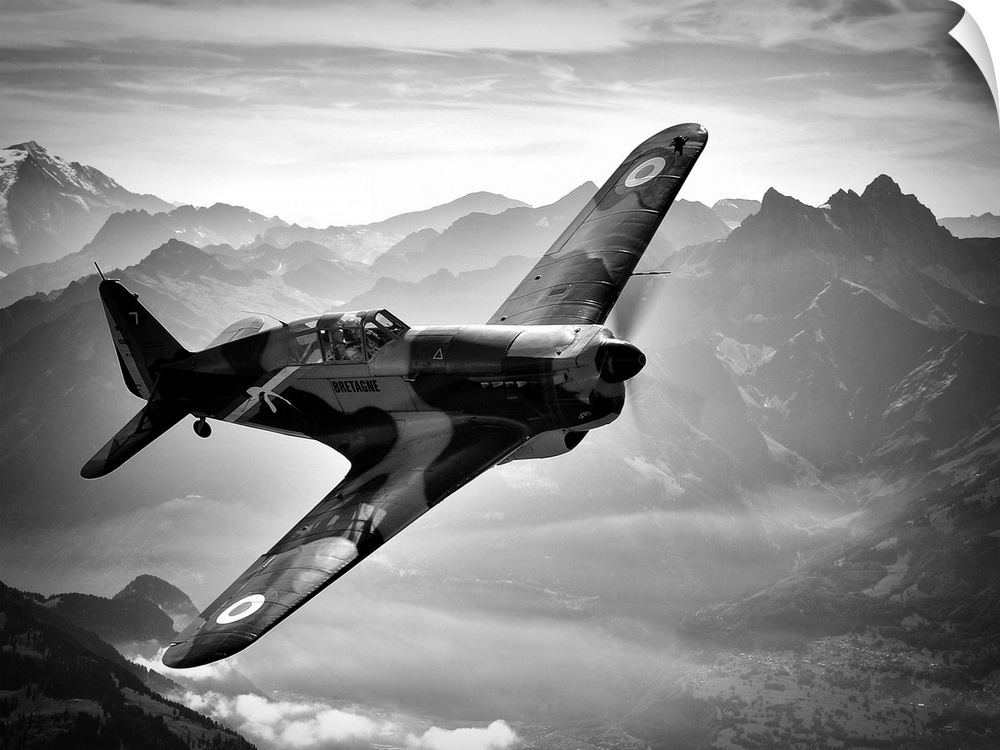 Black and white image of a vintage airplane flying over the Swiss Alps.