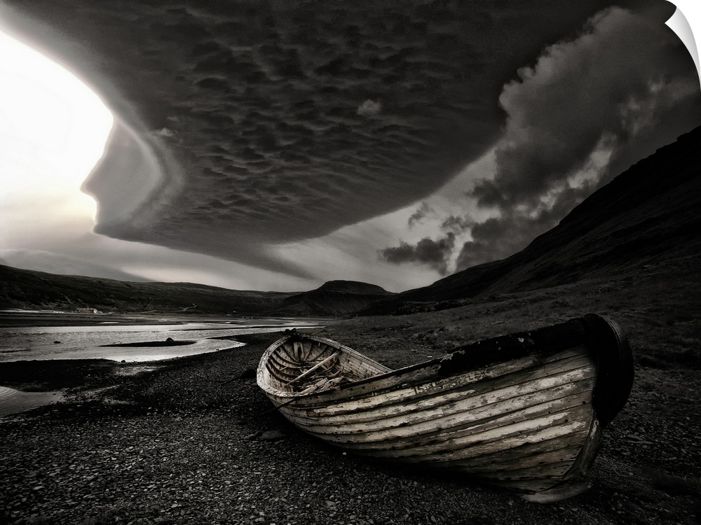 A weathered wooden boat o nthe beach under dark clouds in Iceland.