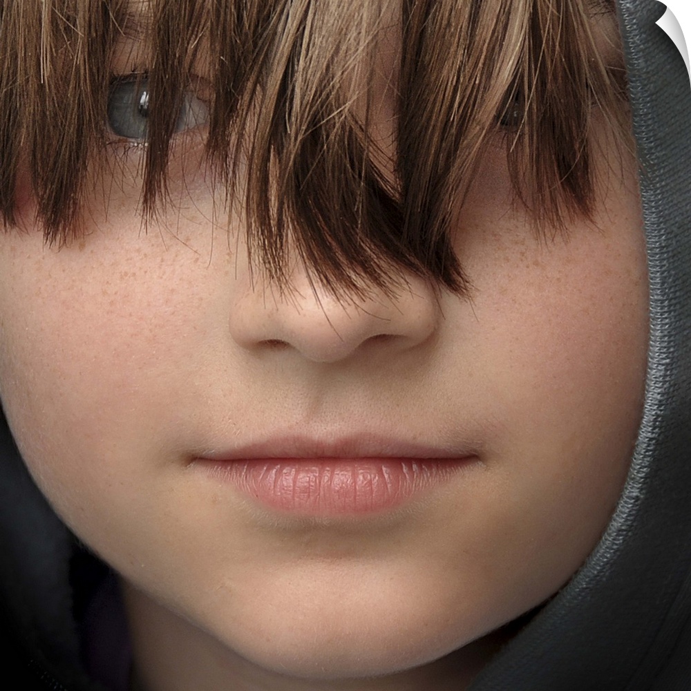 Close-up portrait of a young boy with long bangs covering his eyes.