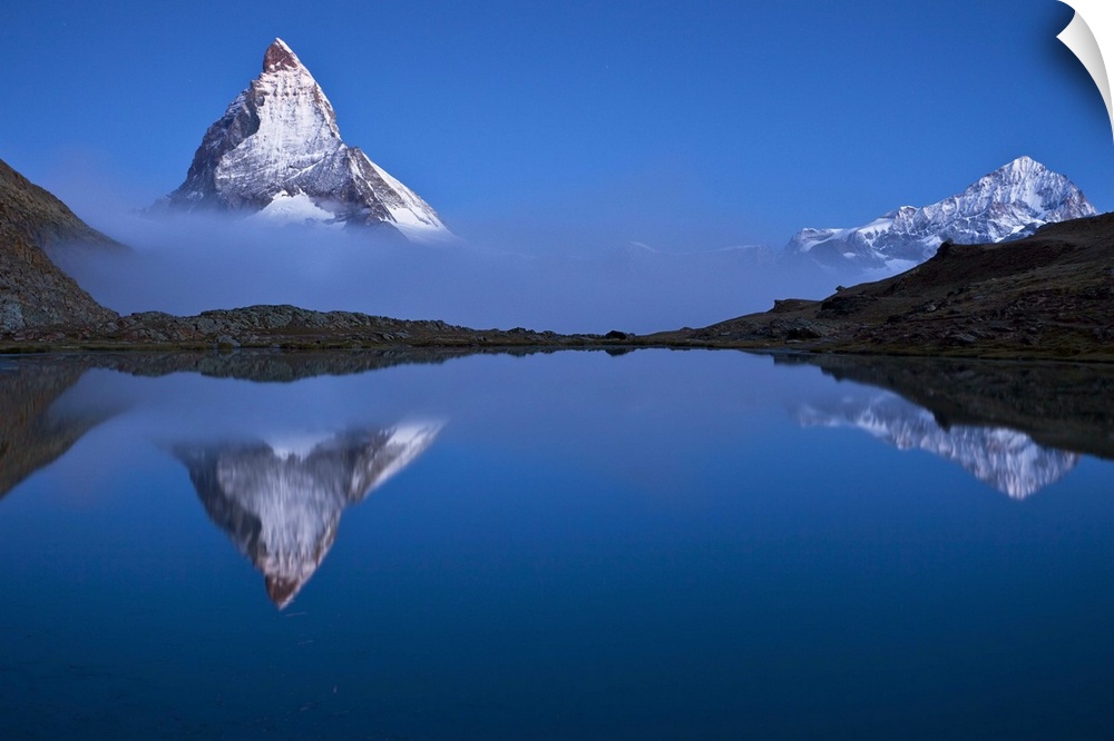 A photograph of the Swiss Alps with the base of the Matterhorn covered in fog.