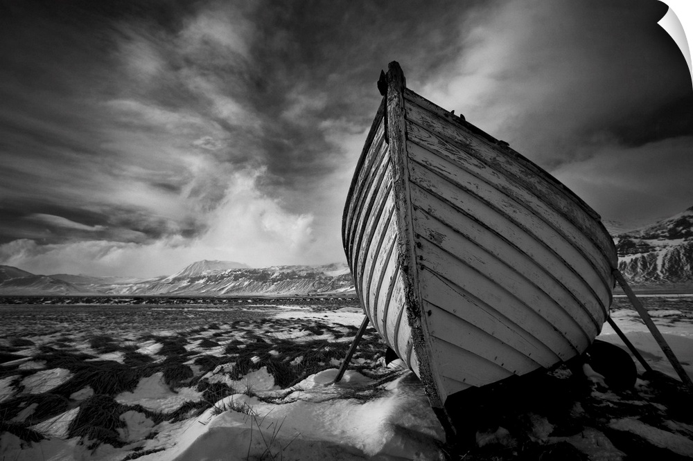 A black and white photograph of a row boat on the shore of an Icelandic beach.