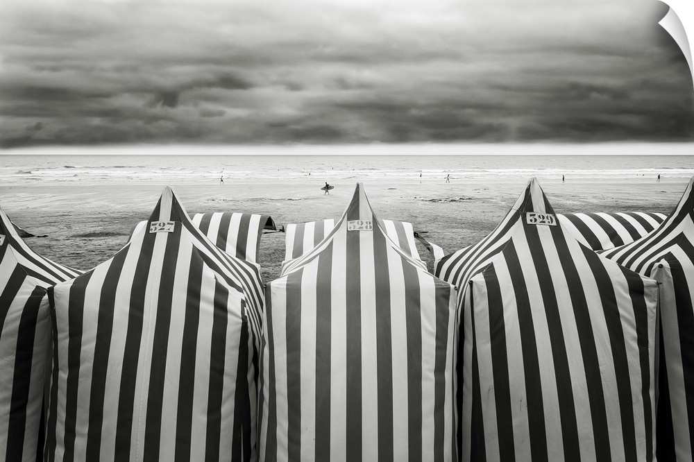 Black and white photograph of  striped beach tents and the ocean in the background at a beach in Spain.