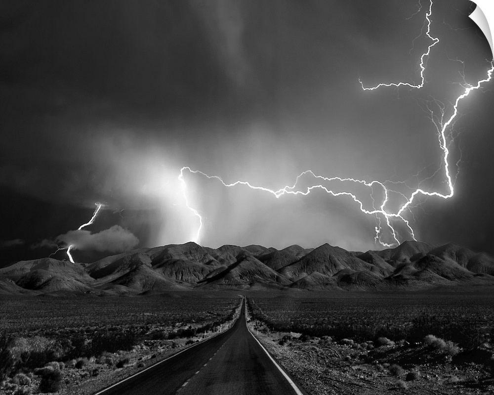 A road leads to mountains in Nevada as lightning bolts shoot across the sky during  a thunderstorm.
