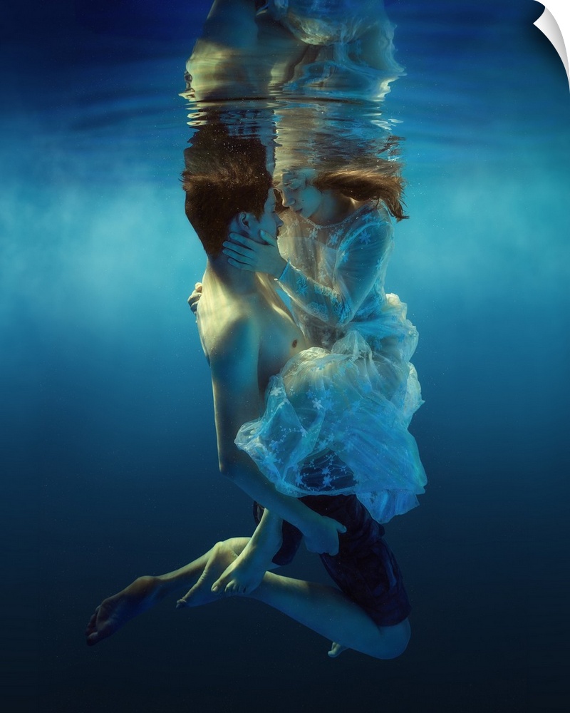 Underwater portrait of a man and woman holding each other, about to kiss.