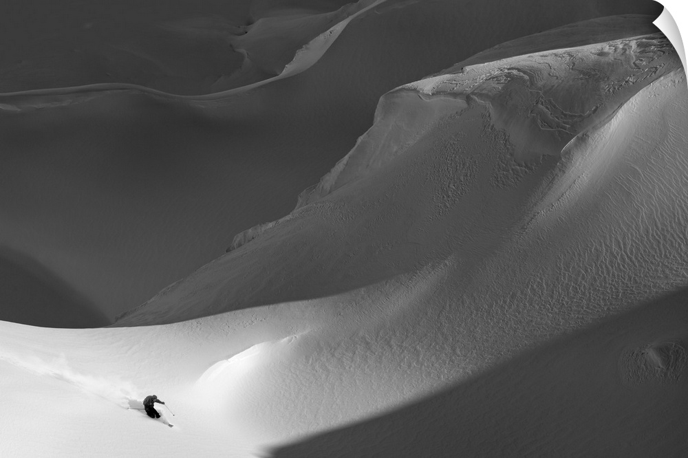 A skier on the side of a treacherous snowy mountain.