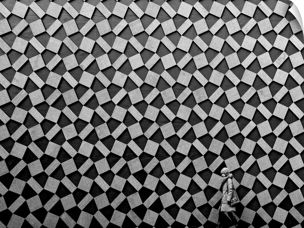 A woman walks past a wall decorated with rectangular shapes, forming an abstract pattern.