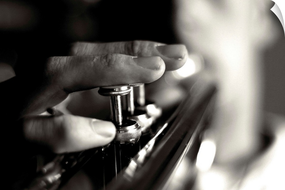 Close up image of a person playing the trumpet, focusing on the fingers and buttons.