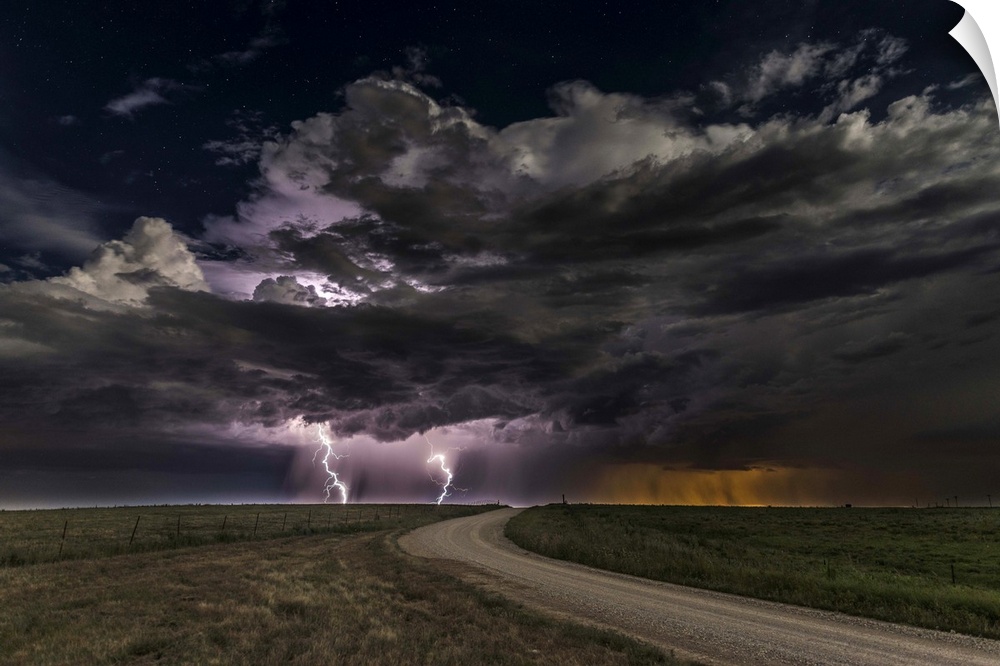 Dramatic clouds throw down bright purple bolts of lightning on a prairie landscape.