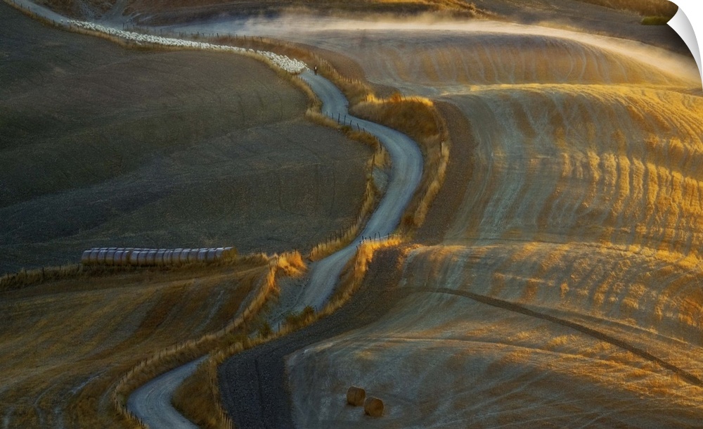 Aerial view of a road winding through a rural landscape in the early morning.