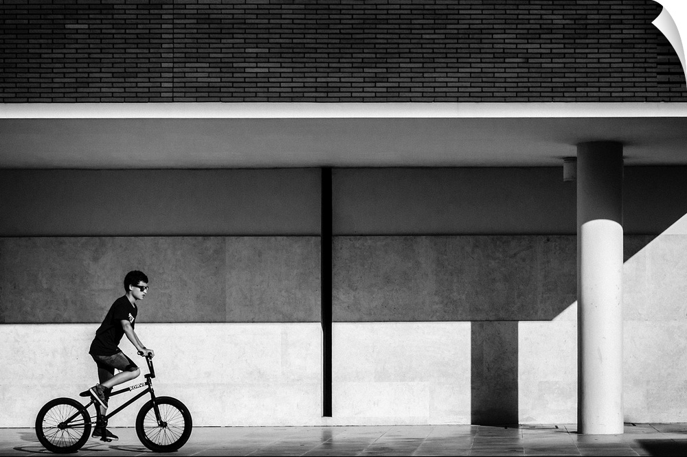 a black and white photograph of a boy riding a bike.