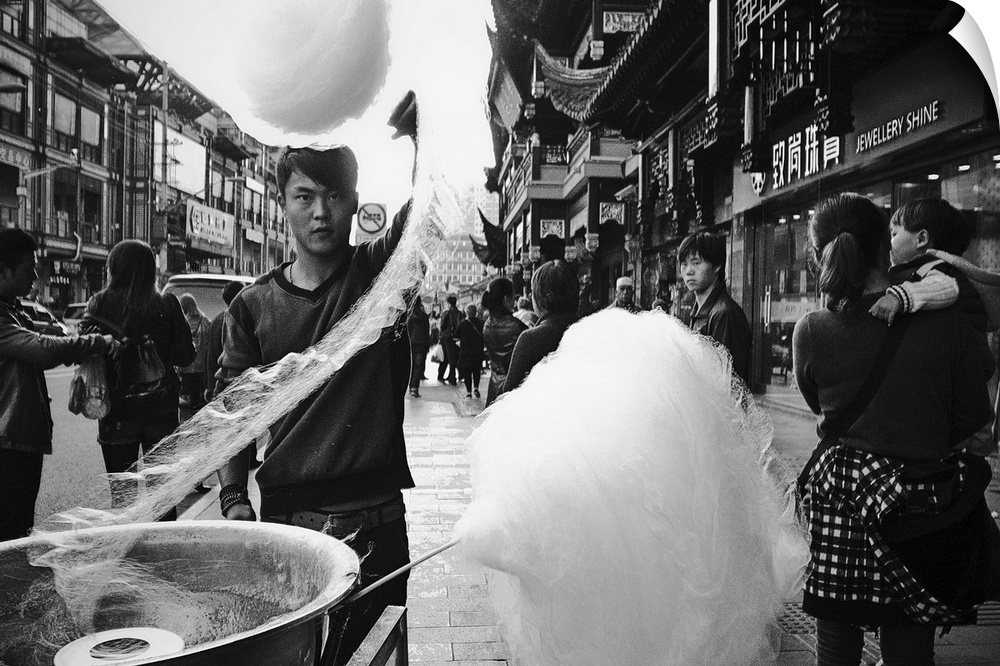 Man twirling cotton candy onto a stock in the streets of Shanghai, China.