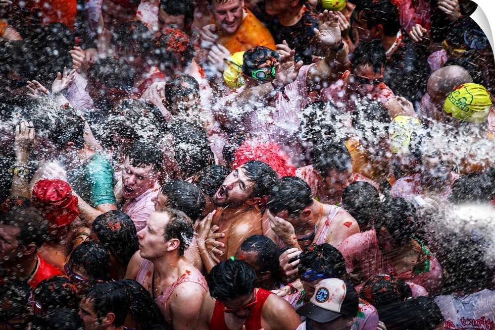 A large group of men in the street being sprayed with water.