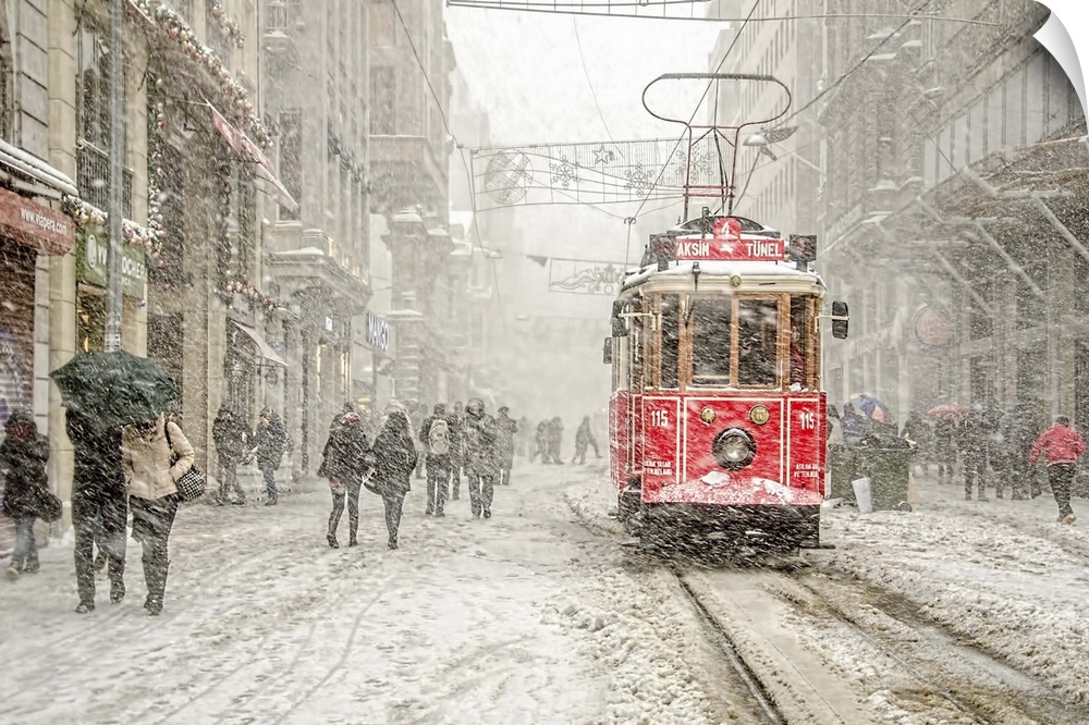 A snowstorm raining down on a city with a red street car in the street.