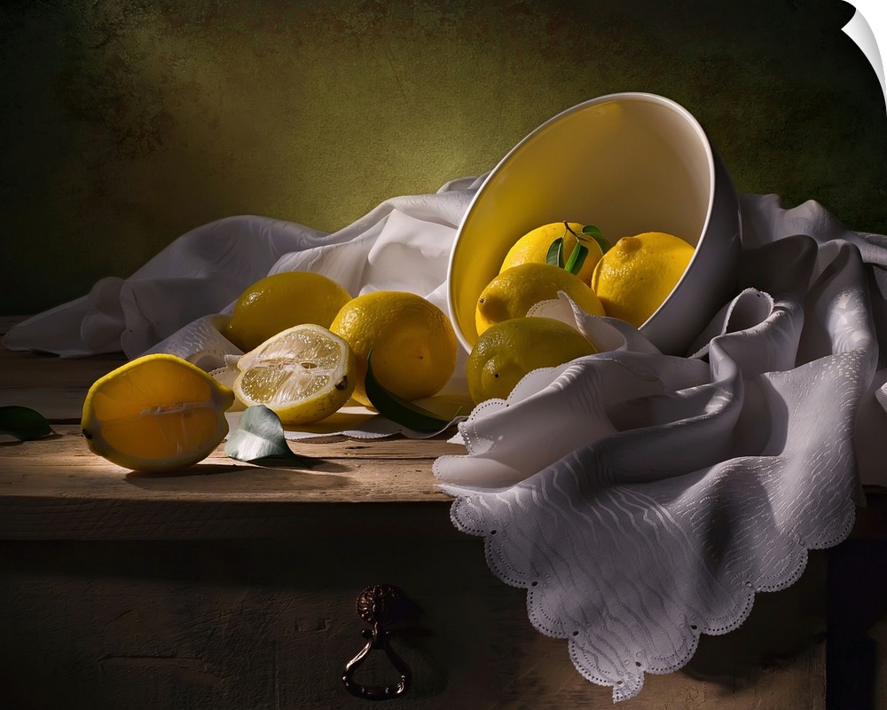 A bowl of lemons on a white cloth, one split in half.