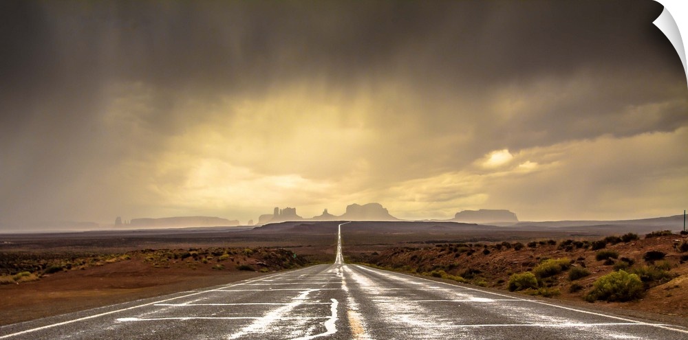 Road leading towards the rock formations in Monument Valley under a stormy sky.