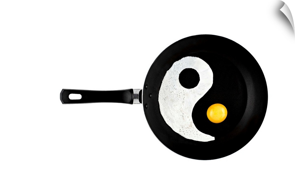 A frying pan with an eggwhite and yolk separated to resemble a yin yang symbol.