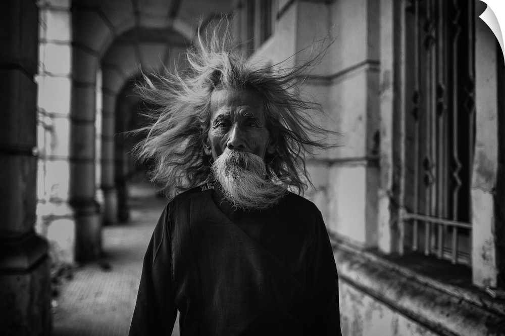 A portrait of an old man with wind blown hair.