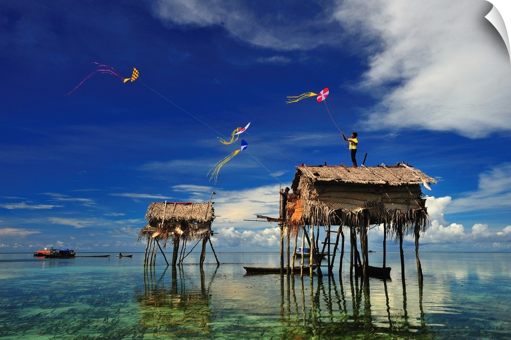 Kites flying over a group of houses on stilts in the ocean, Sabah, Malaysia.