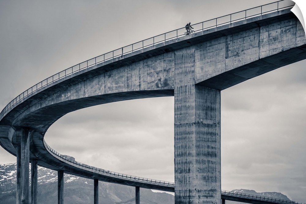 A biker riding across the top of a tall concrete bridge, Norway.