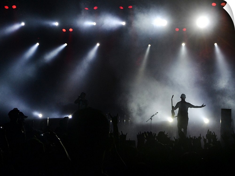 A musician greets his fans on stage under the bright lights during a concert.
