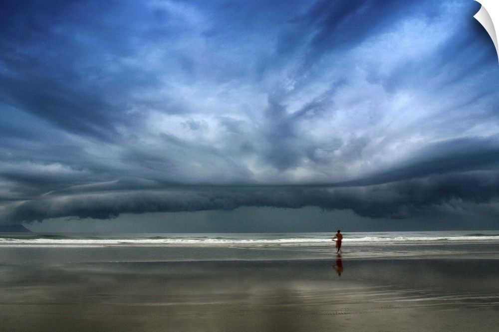 Adventurous surfer heads into the water, undeterred by the approaching stormclouds.