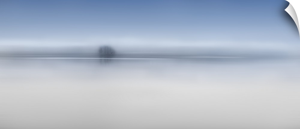 A small group of trees sit on the edge of the Columbia river casting reflections through the layers of fog, Oregon.