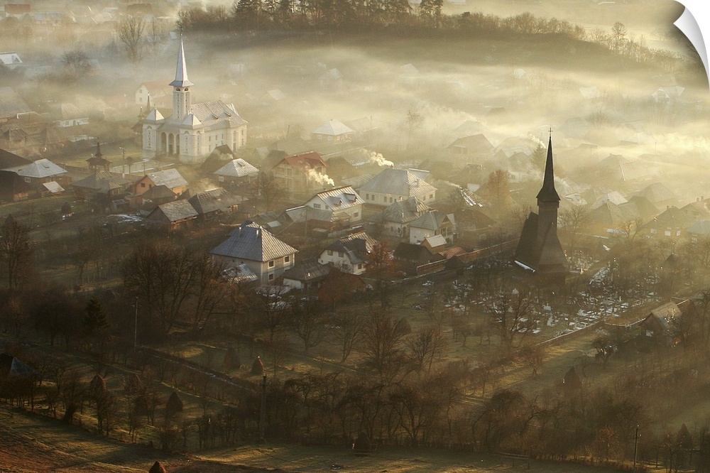 Morning view of a village with the tops of buildings rising out of the mist.