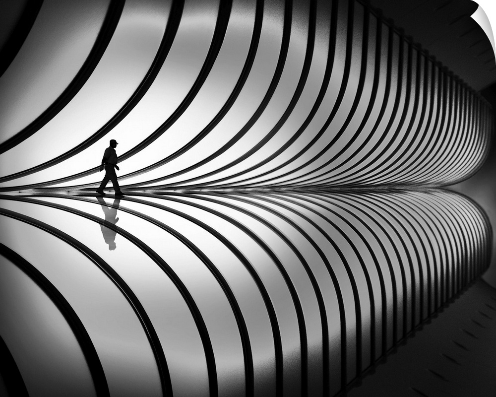 A person walking past a striped, curved wall, with a mirror reflection below.