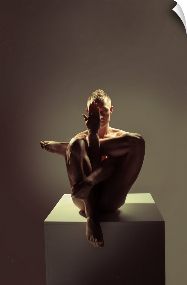 Fine art portrait of a woman sitting on a platform creating angles with her body with dramatic lighting.