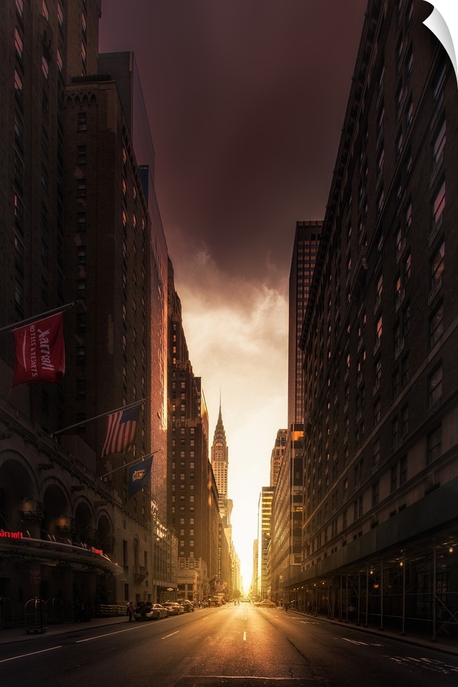 Cityscape photograph of Manhattan with sunlight peeping through the tall buildings and the Chrysler Building in the distance.