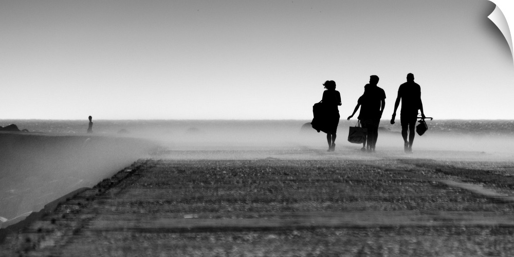 A black and white photograph of three silhouetted figures walking toward a mist.