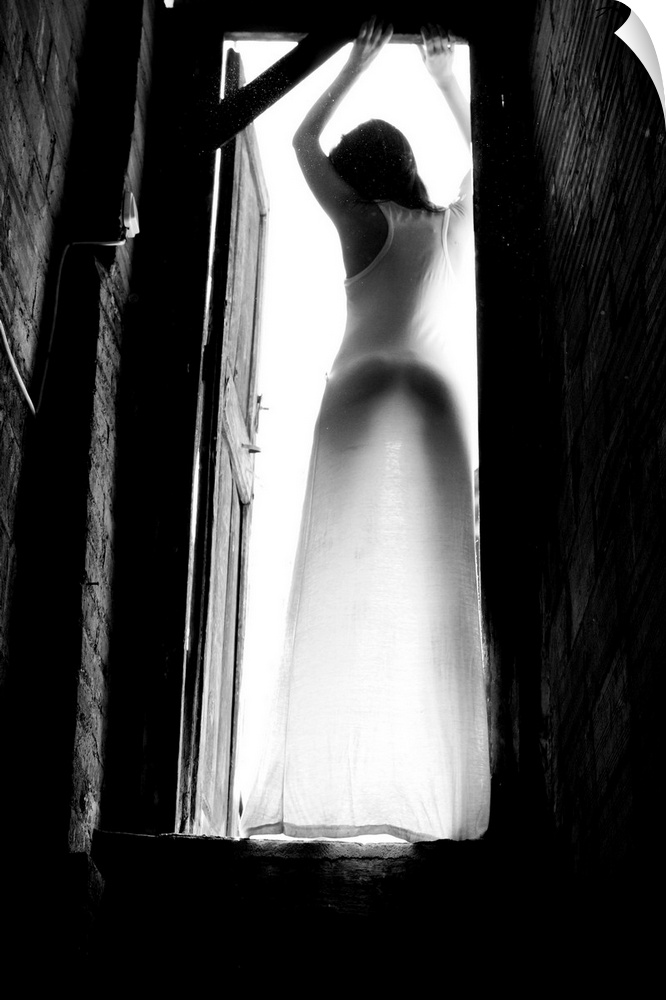 Black and white portrait of a woman standing in a doorway with light shining in.