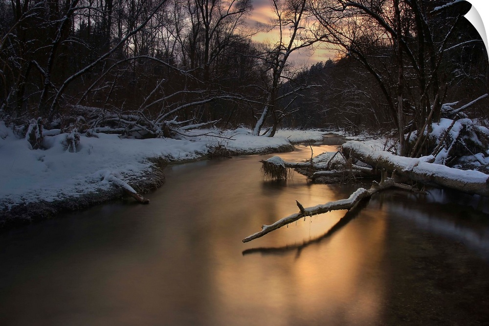 A serene river reflecting evening light in a snowy forest in the winter.